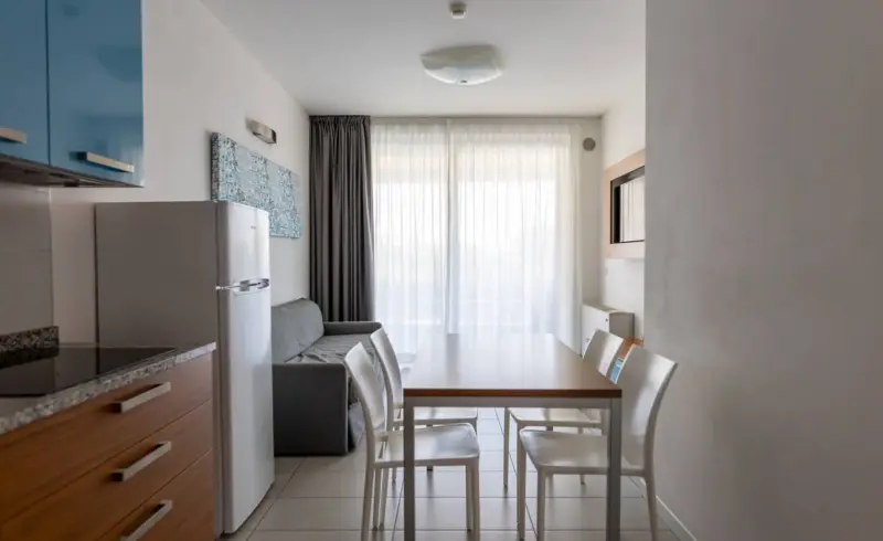Cucina moderna con tavolo, sedie e divano grigio.