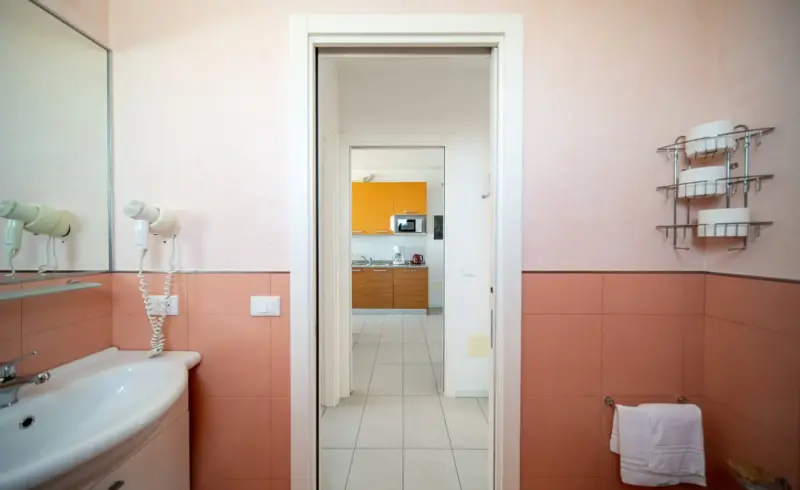 Bagno che dà su cucina con arredo moderno.