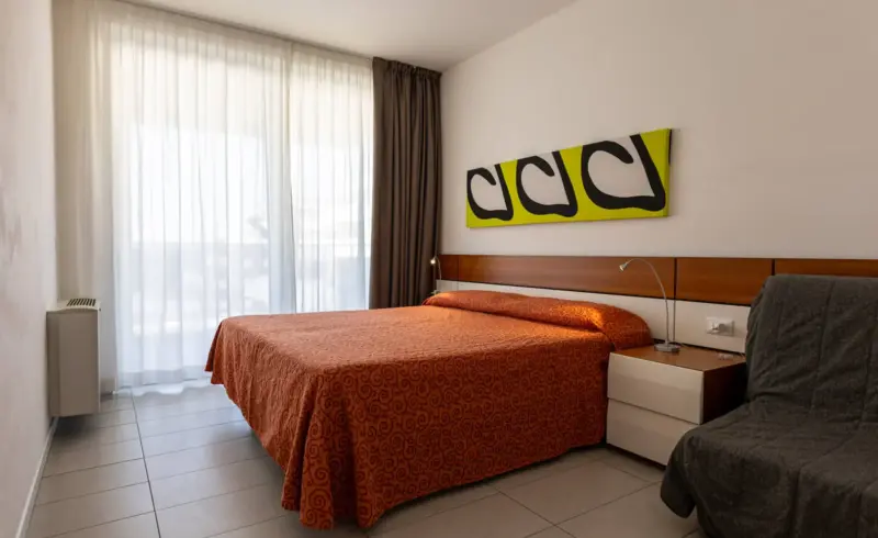 Camera da letto moderna con tende e dipinto astratto.
