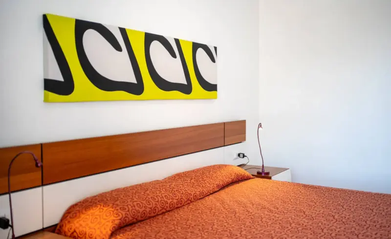 Camera con letto matrimoniale, decorazioni colorate e lampade.