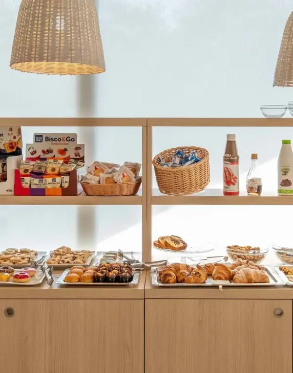 Buffet colazione con brioche, cereali e bevande.