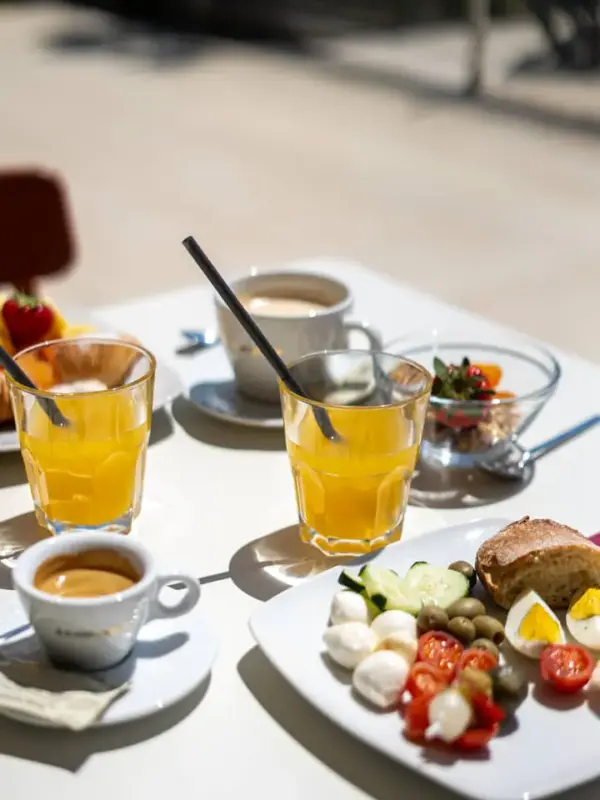 Colazione all'aperto con succo, caffè e piatto assortito.