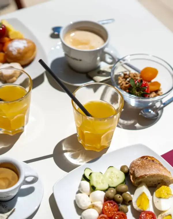 Colazione varia su tavolo con succhi e caffè.