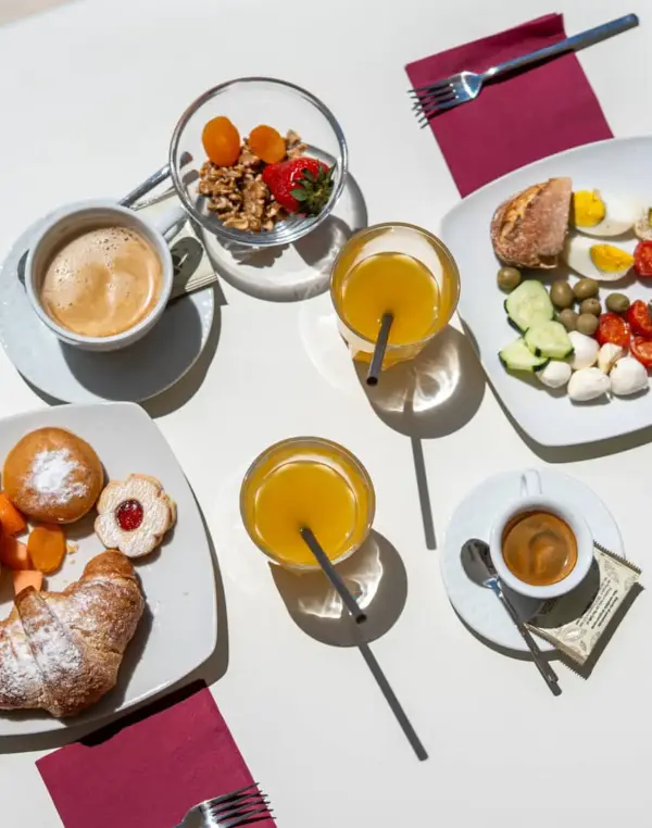 Colazione italiana con cornetti, frutta e caffè.