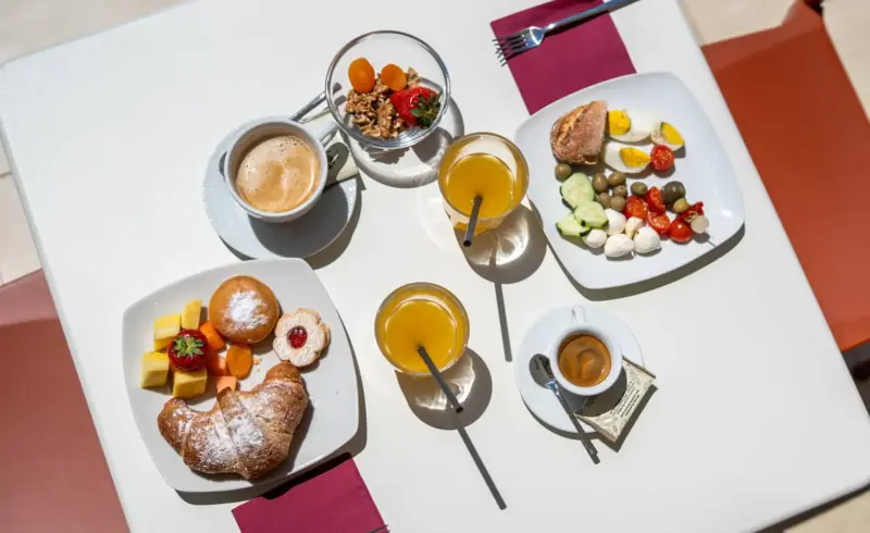 Colazione italiana con cornetti, frutta e caffè.