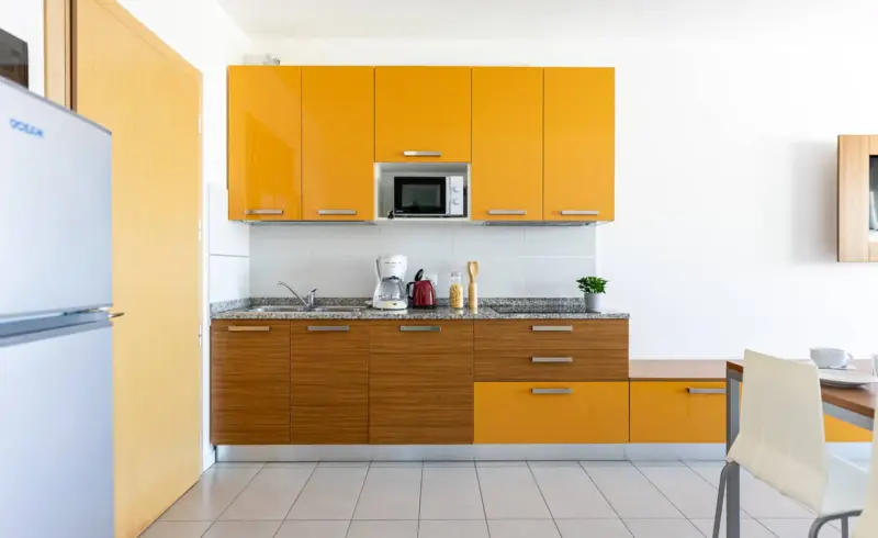 Cucina moderna con mobili gialli e accessori vari.