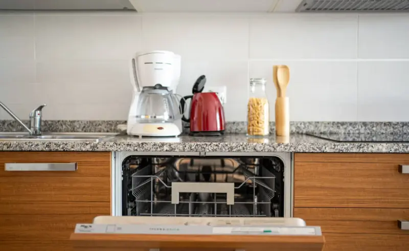 Cucina moderna con lavastoviglie aperta e piccoli elettrodomestici.