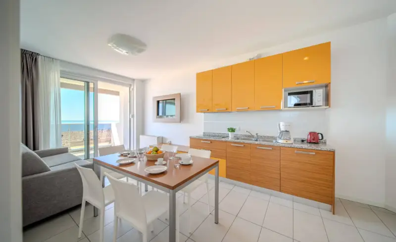 Cucina moderna con tavolo apparecchiato e vista mare.