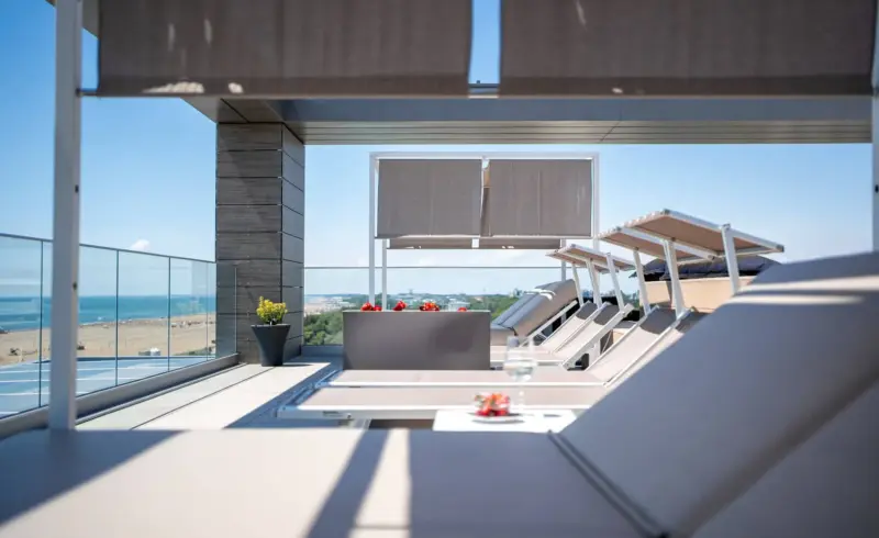 Terrazza con lettini prendisole e vista sul mare.