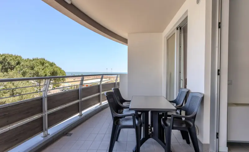 Balcone moderno con vista mare, tavolo e sedie.
