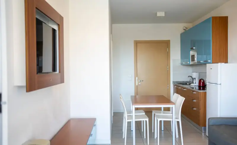 Cucina moderna con tavolo, sedie e frigorifero bianco.