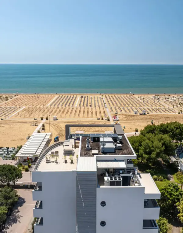 Vista aerea di una spiaggia con piscina e mare.