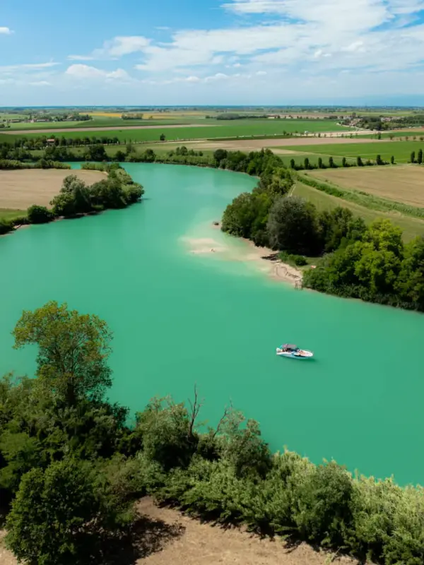 Fiume turchese tra campi verdi e cielo